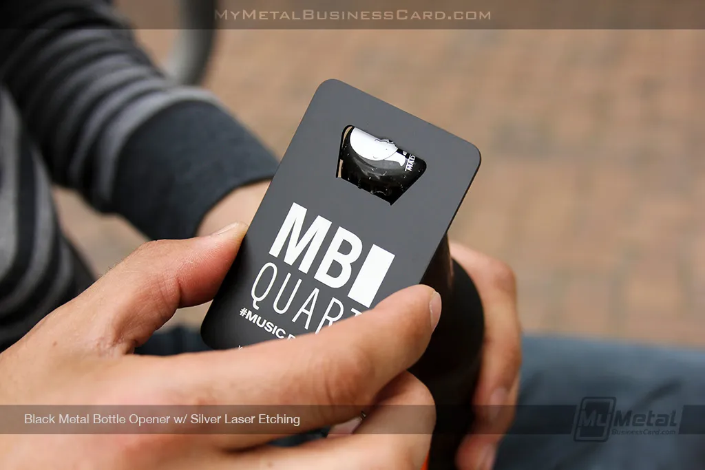metal bottle opener business card with black metal finish and silver laser etching on surface opening a beer bottle
