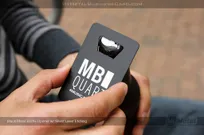 metal bottle opener business card with black metal finish and silver laser etching on surface opening a beer bottle